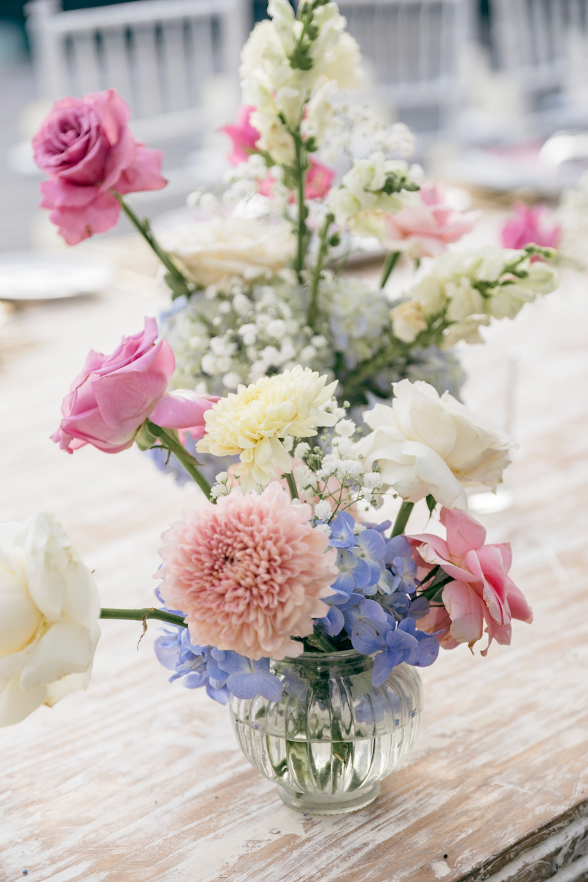 Pastel pink and blue floral centerpiece on a rustic table at a destination wedding in Bali