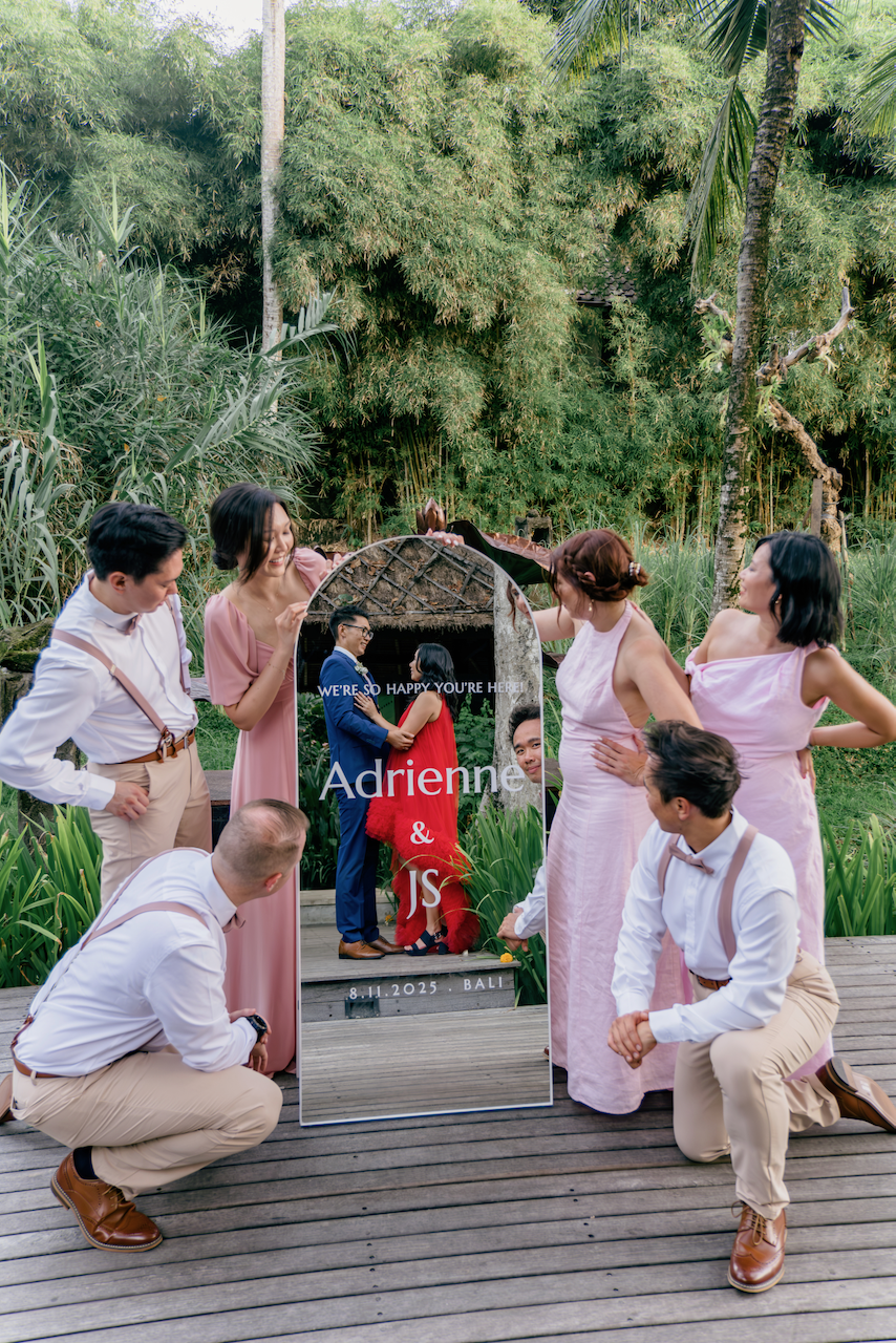Bridal party admiring a custom mirror welcome sign reflecting the couple at their tropical celebration