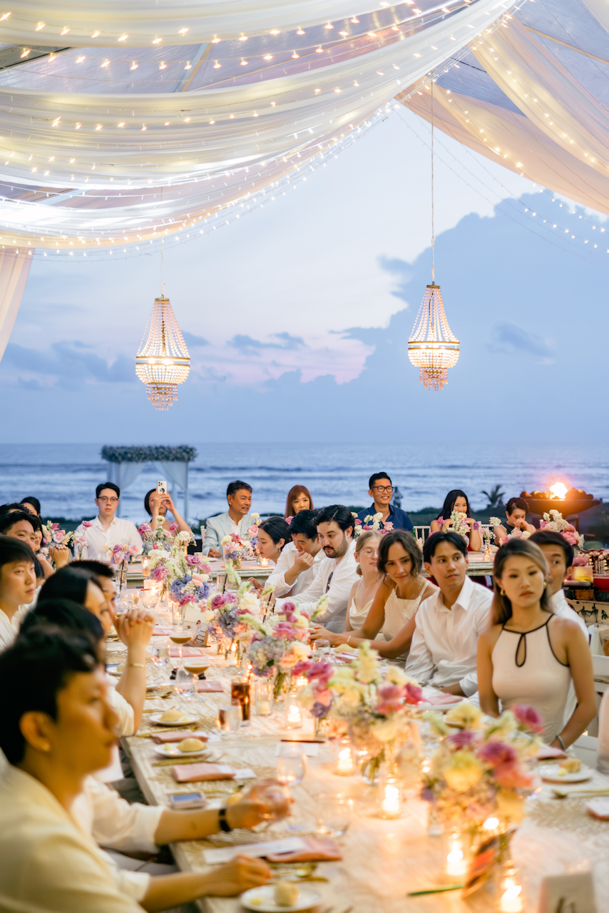 Sunset view of a beautiful coastal wedding reception with illuminated chandeliers and an ocean backdrop