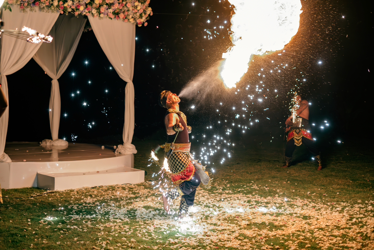 Traditional Balinese fire dancer performing at an outdoor evening wedding reception