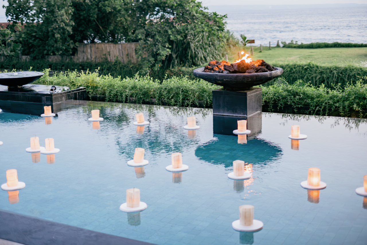 Outdoor swimming pool at dusk filled with floating candles for an elegant Bali wedding planned by Silver Lace Weddings