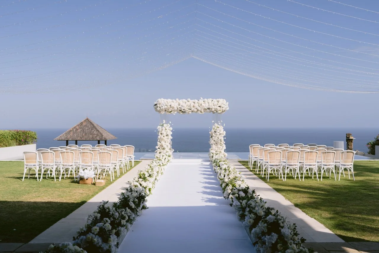 Ocean view ceremony setup with white floral aisle at Surga Estate Bali