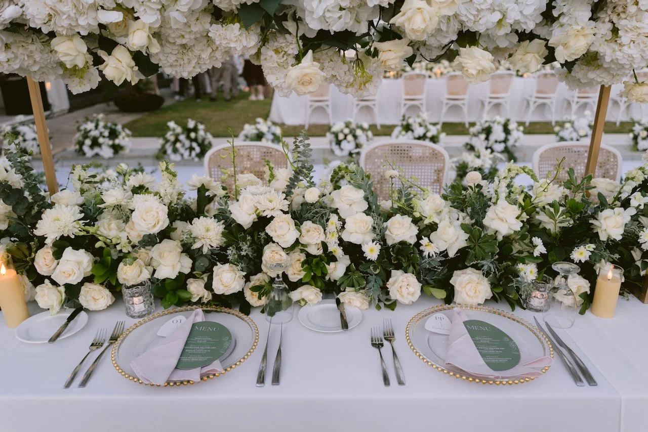 Long table wedding reception setup with white flowers and ocean view in Bali