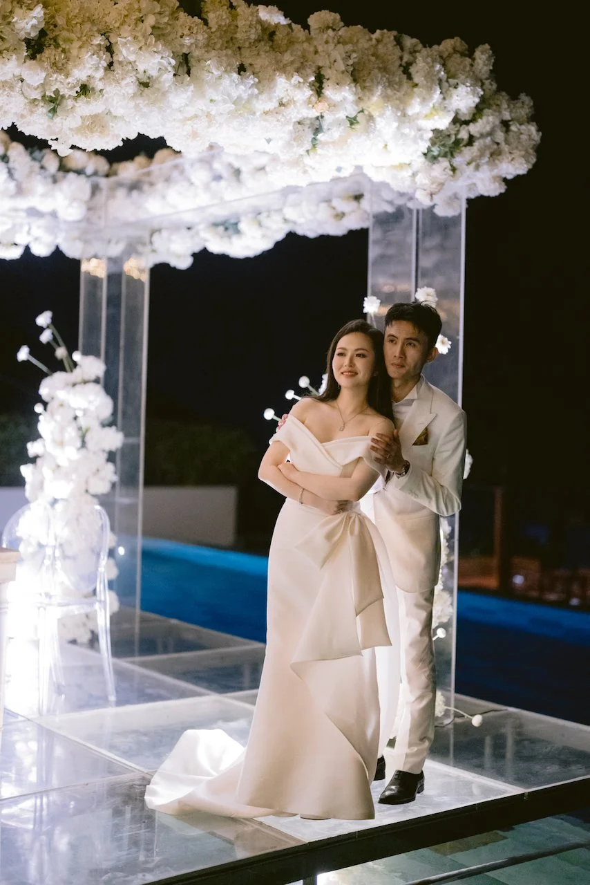 Bride and groom portrait under floral canopy at Bali evening reception