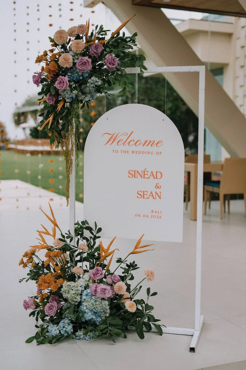 Arched modern wedding welcome sign framed by vibrant tropical florals at Villa Phalosa Bali.