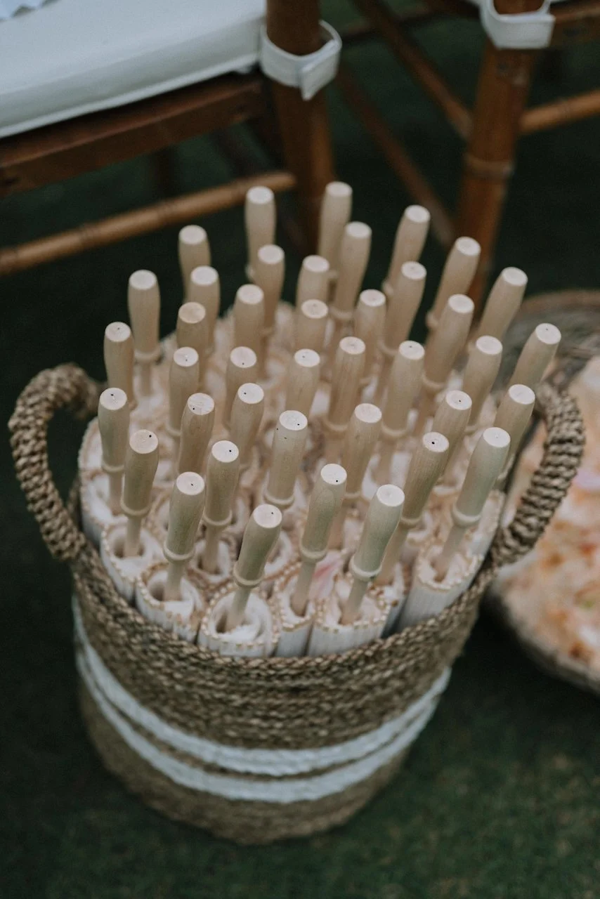 Woven basket filled with white paper parasols for guest comfort at a sunny outdoor Bali ceremony.