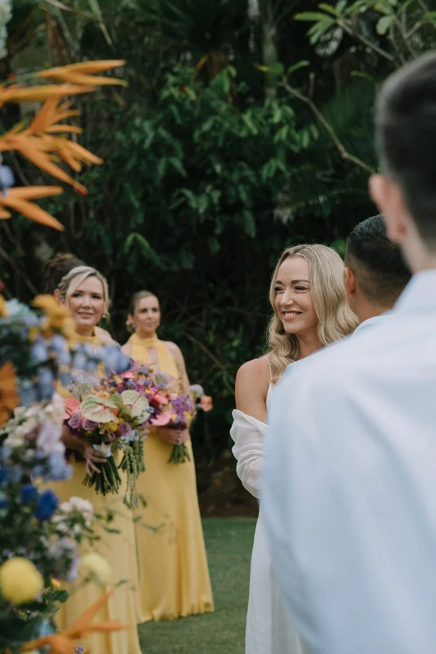 Radiant bride smiling lovingly at her groom during their tropical Bali wedding ceremony.