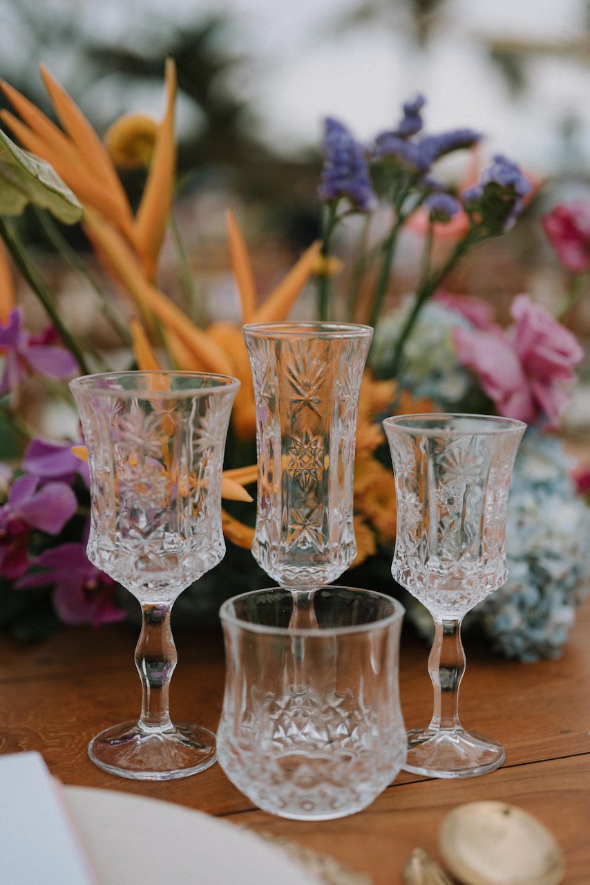 Ornate crystal glassware centerpiece details with bright florals at an outdoor wedding reception.
