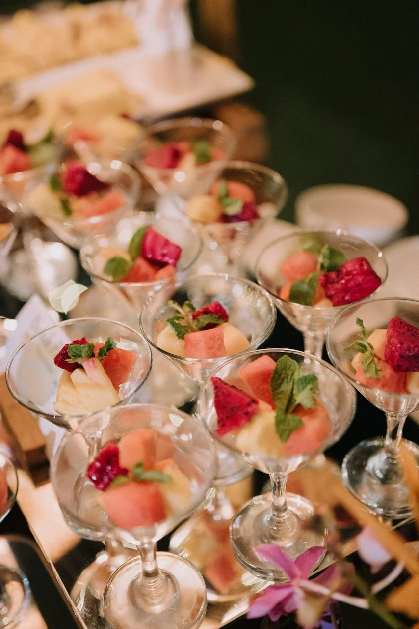 Elegant catering station serving fresh fruit cups in glass goblets for a sweet wedding treat.