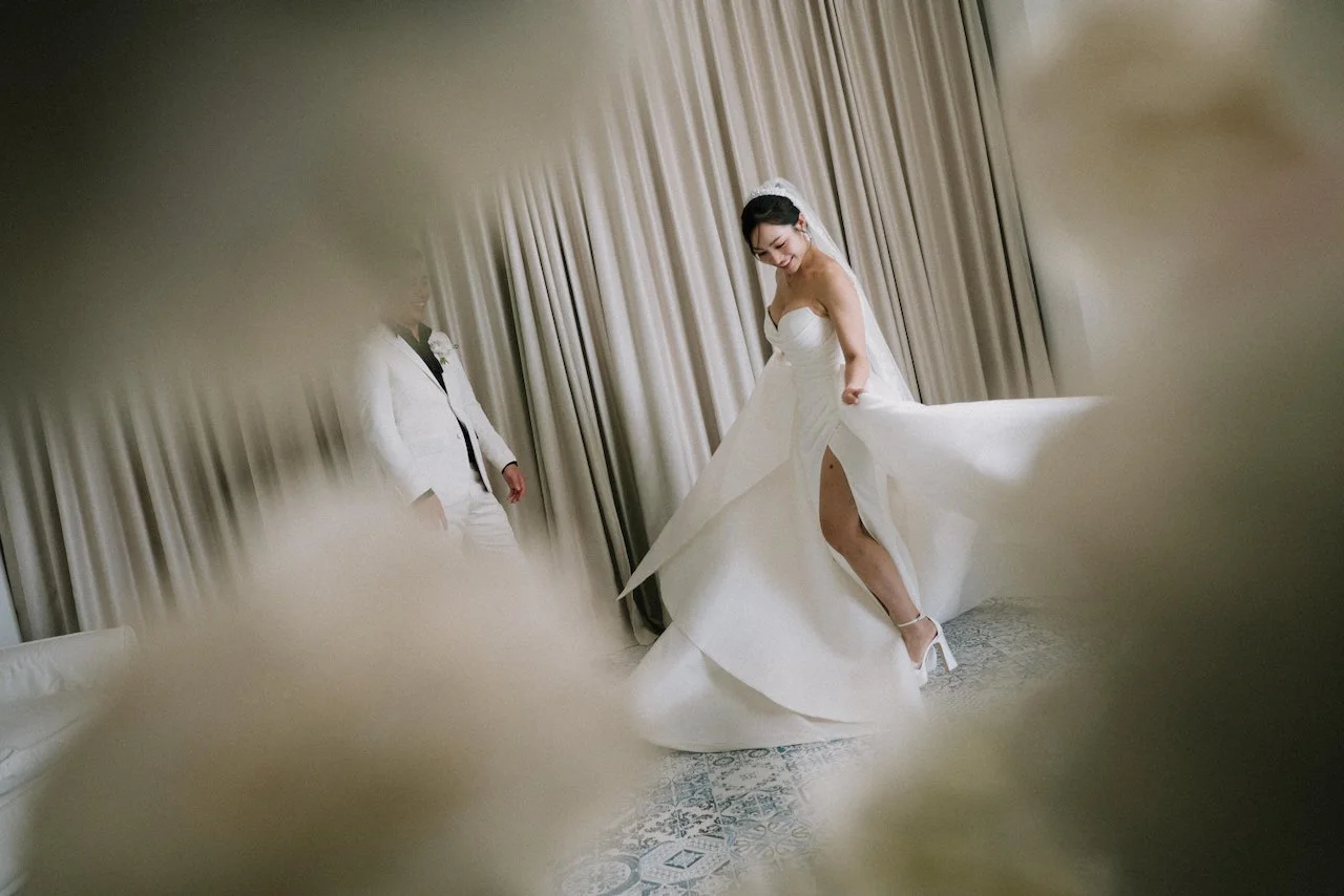 Bride twirling in a chic high-slit wedding dress as the groom smiles in Bali.
