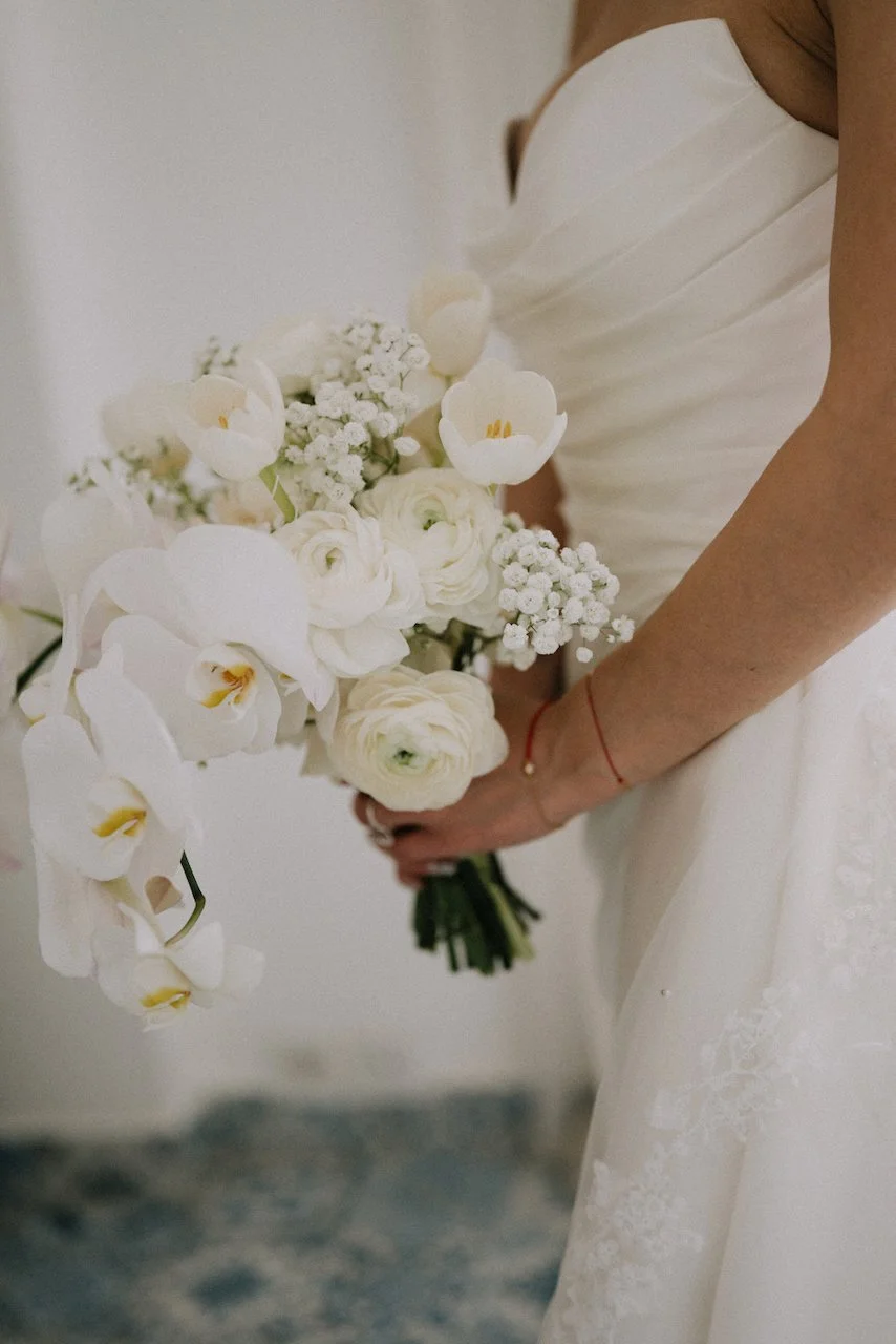 Close-up of a modern all-white bridal bouquet featuring orchids, tulips, and roses.