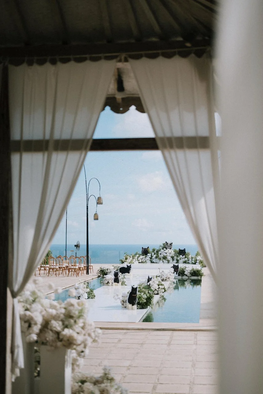 Scenic view through draped curtains of a floating wedding aisle overlooking the Bali ocean.