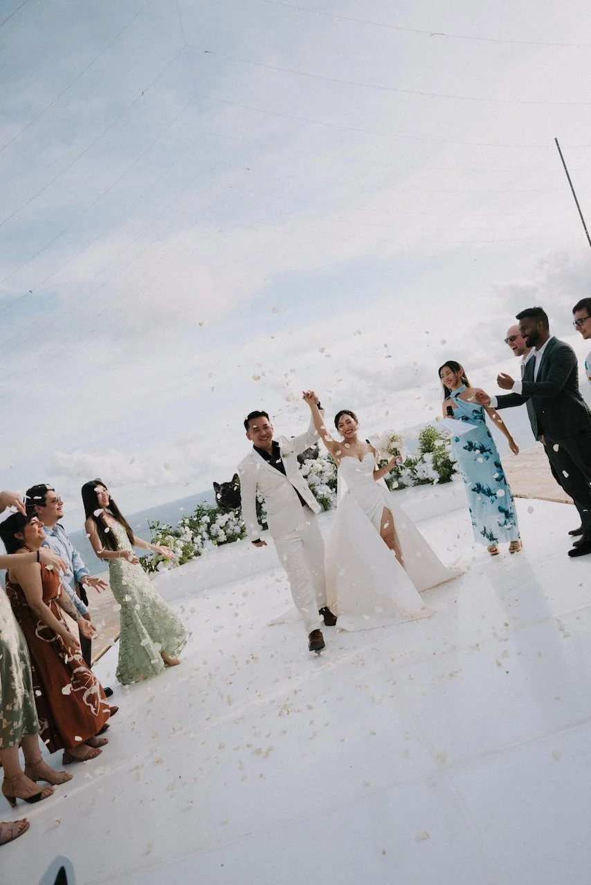 Joyful newlyweds walking down the aisle during a white rose petal toss recessional.