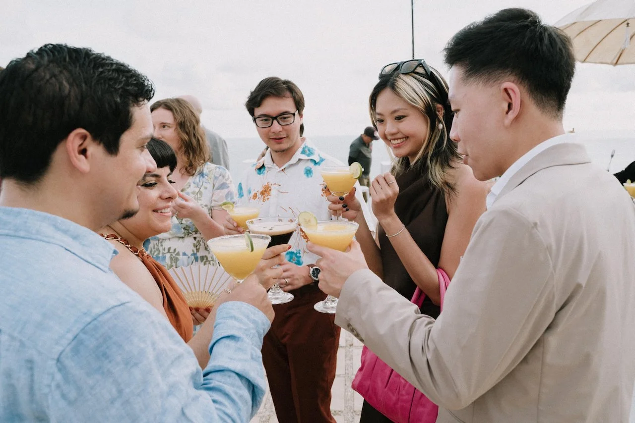 Wedding guests mingling and toasting with signature cocktails overlooking the Uluwatu coastline.