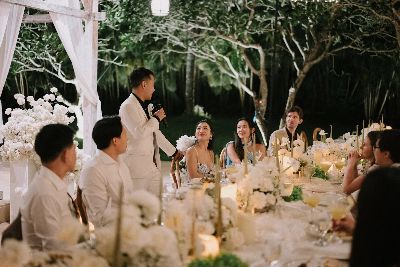 Groom giving a heartfelt reception speech to guests as the bride smiles in her sparkly fringe party dress.
