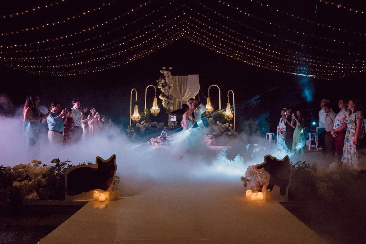 Romantic first dance on a floating pool stage surrounded by low fog and fairy lights in Uluwatu.