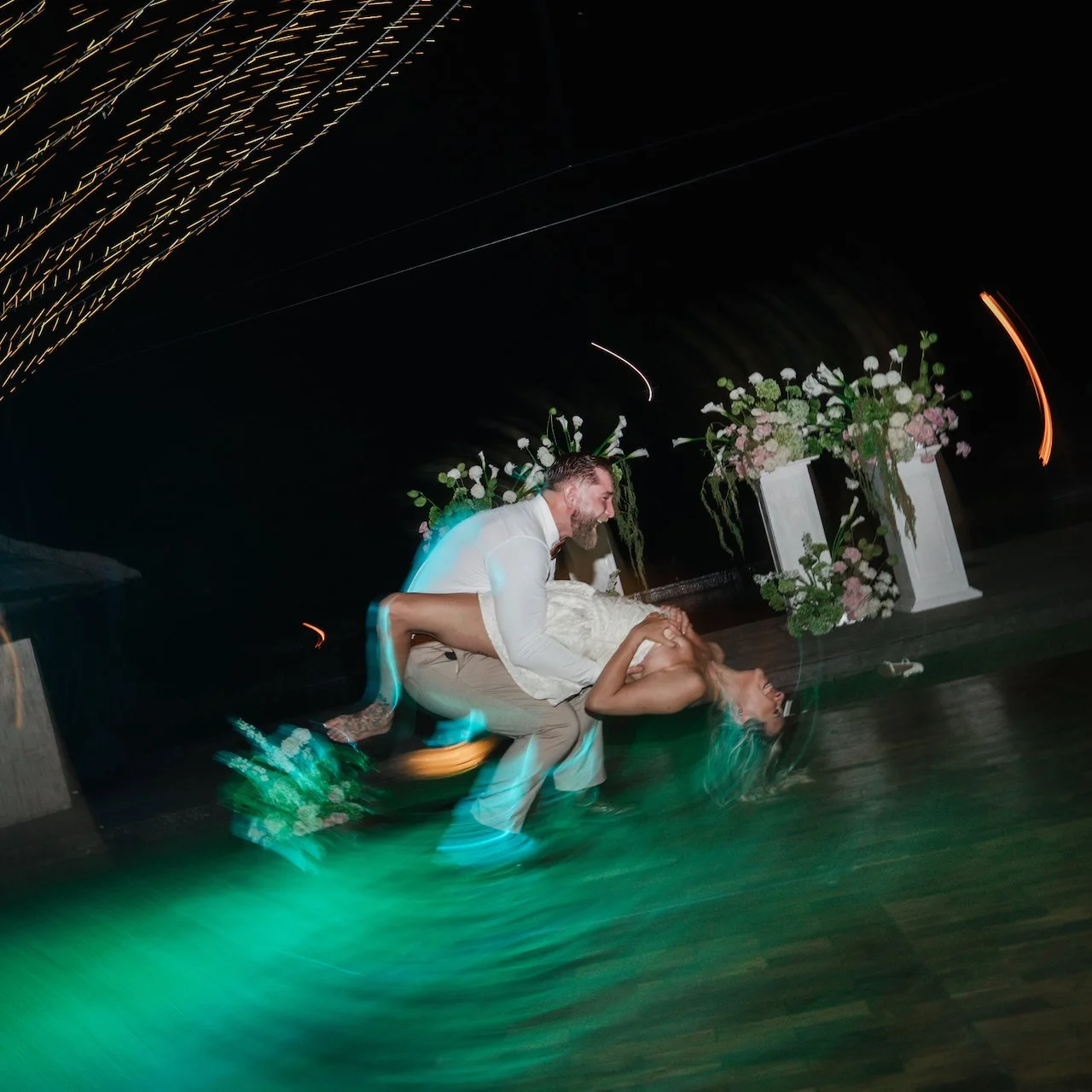 Groom dipping his bride on the dance floor captured with an energetic long-exposure flash effect.