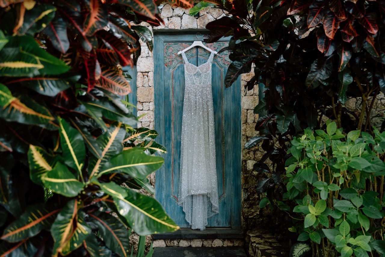 Lace bridal gown hanging on a blue door at Villa Pemutih.