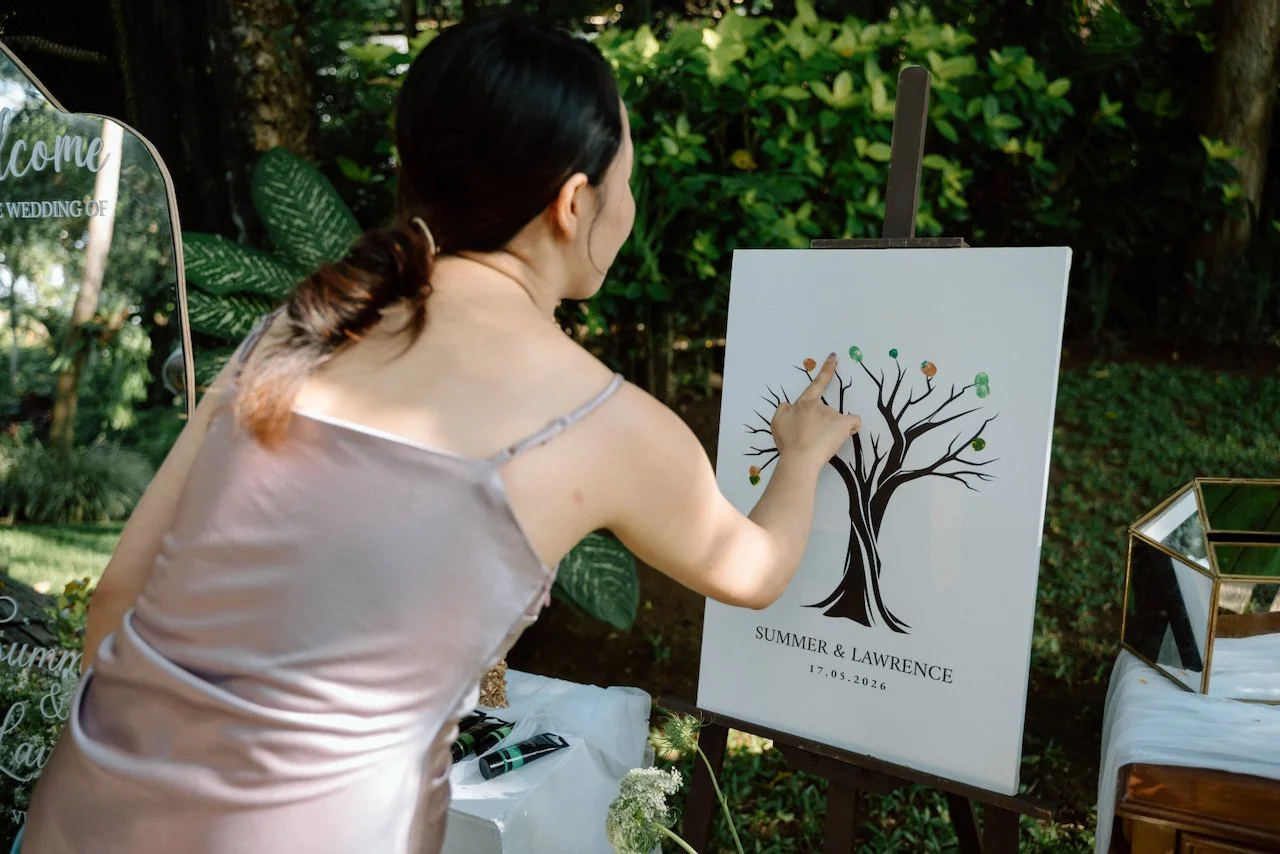 Guest adding a fingerprint to an inking tree guestbook at a destination wedding.