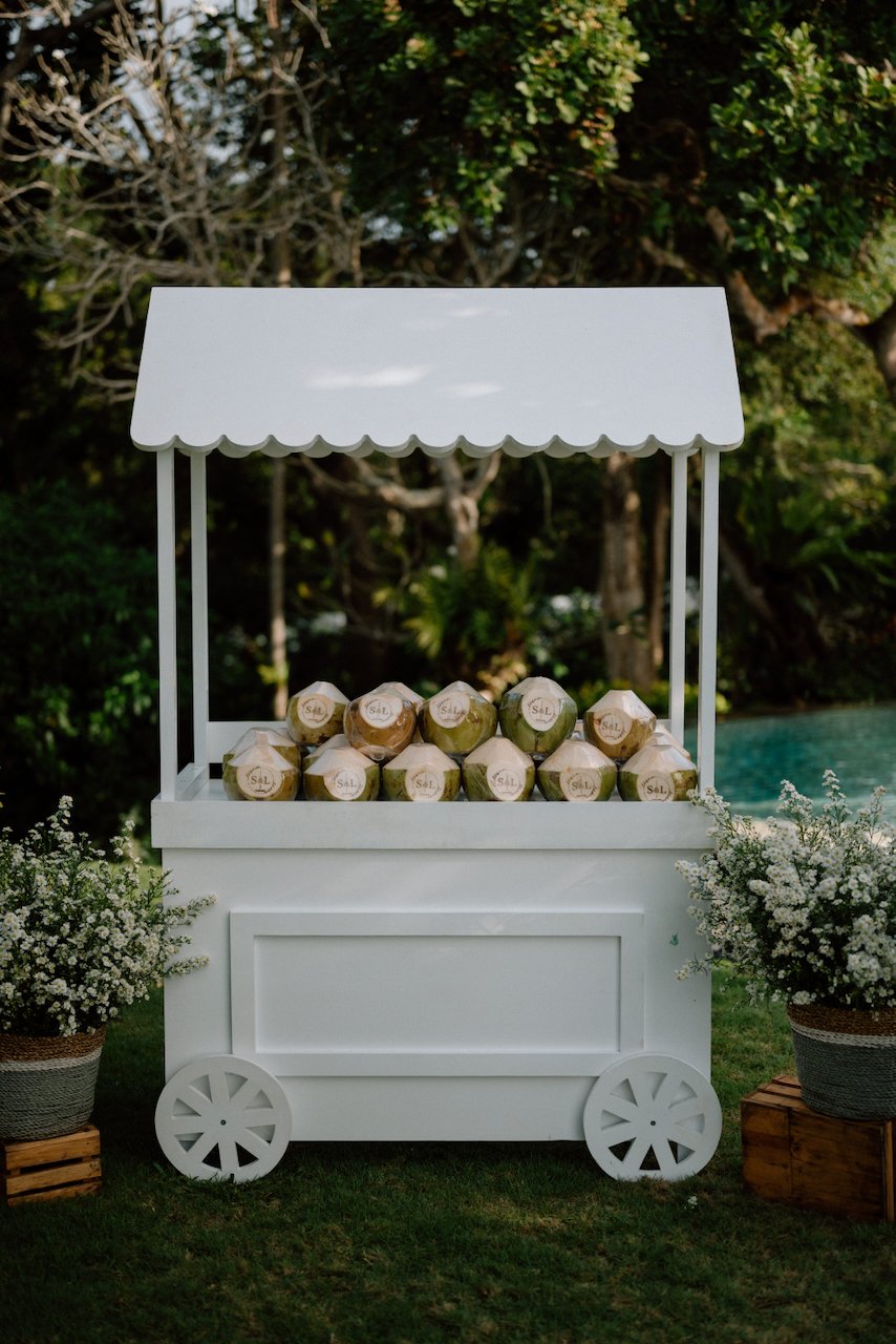 White refreshment cart filled with fresh coconut drinks for Bali wedding guests.