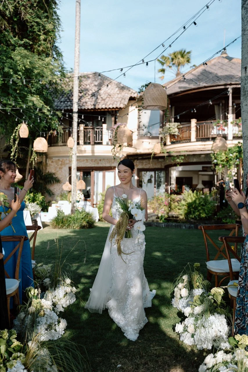 Long shot of a bride walking toward her oceanfront wedding ceremony.