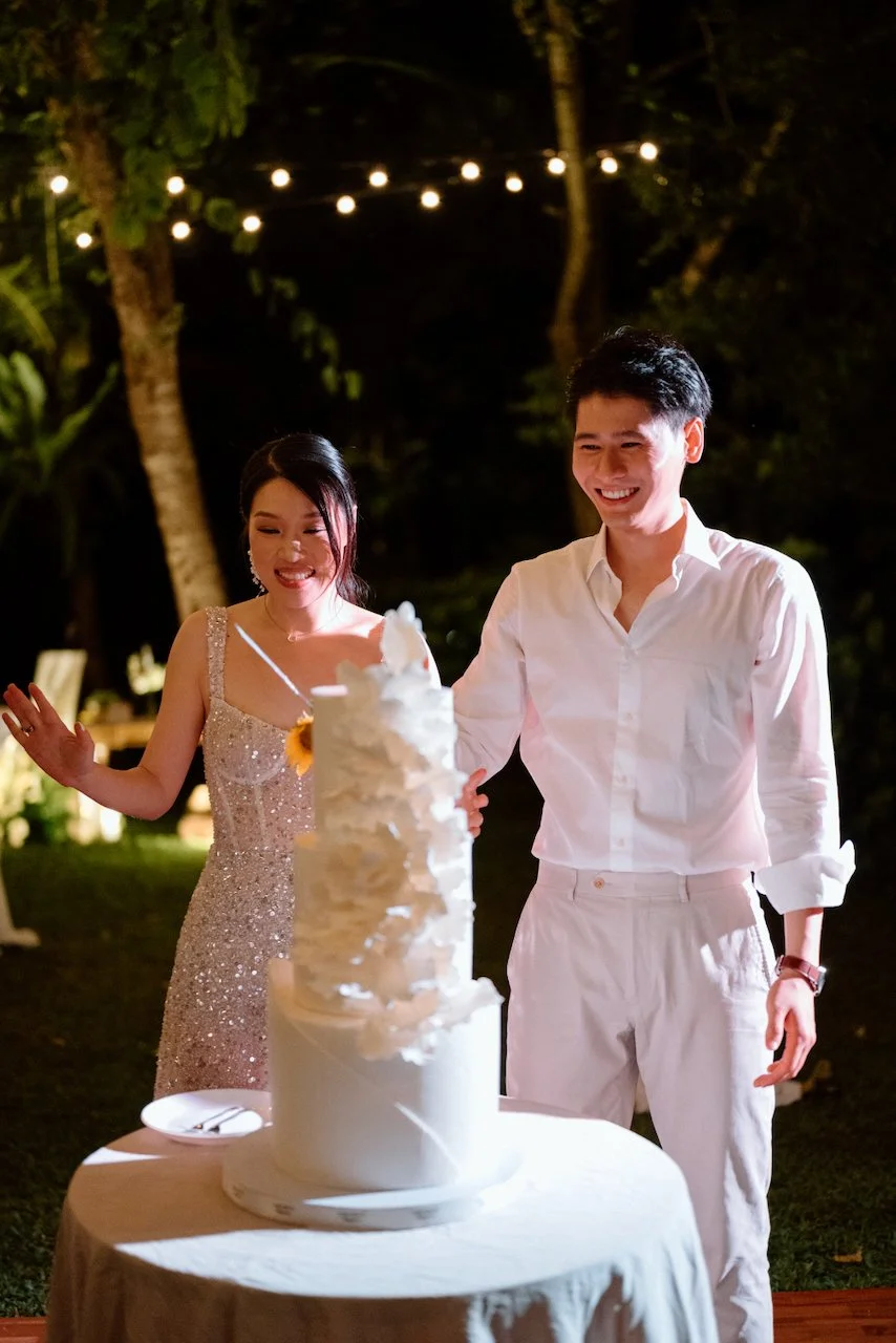 Bride and groom smiling beside their textured white wedding cake.