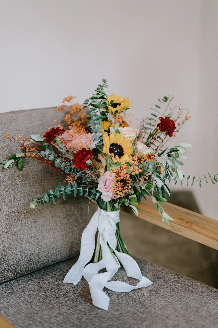 Colourful bridal bouquet featuring roses, sunflowers and seasonal blooms.