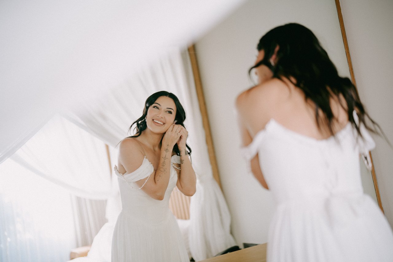 Bride putting on her earrings before the wedding ceremony.