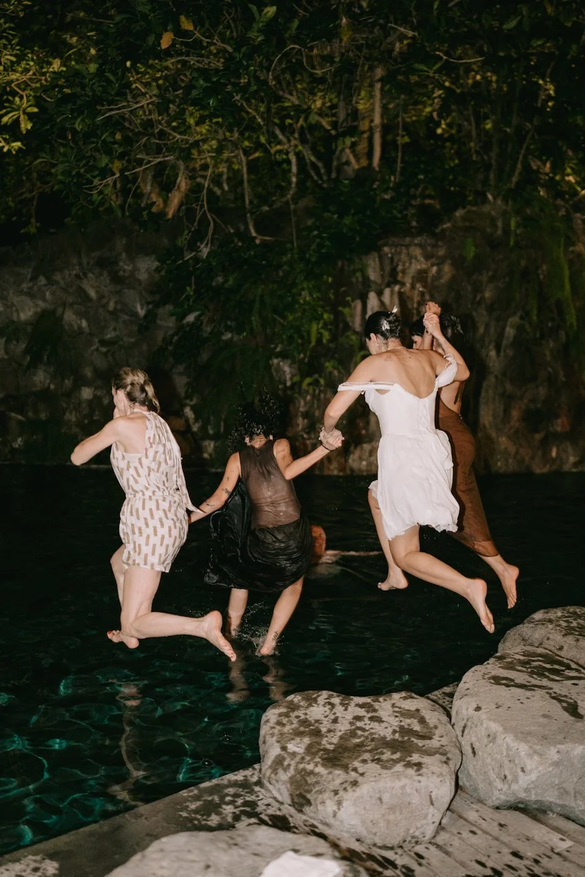 Wedding guests jumping into the pool to celebrate the newlyweds.