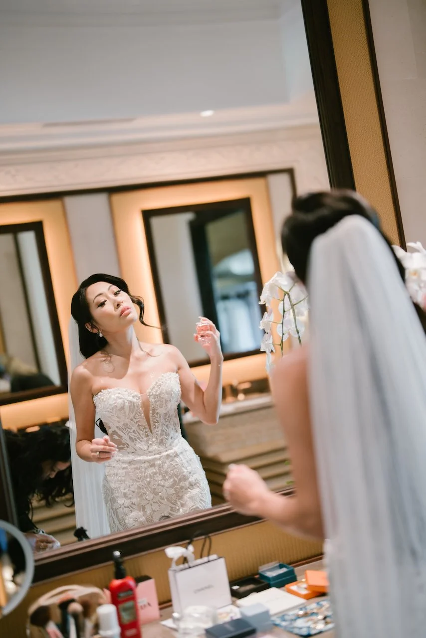 Bride in a beaded wedding dress and veil admiring her reflection in a full-length mirror