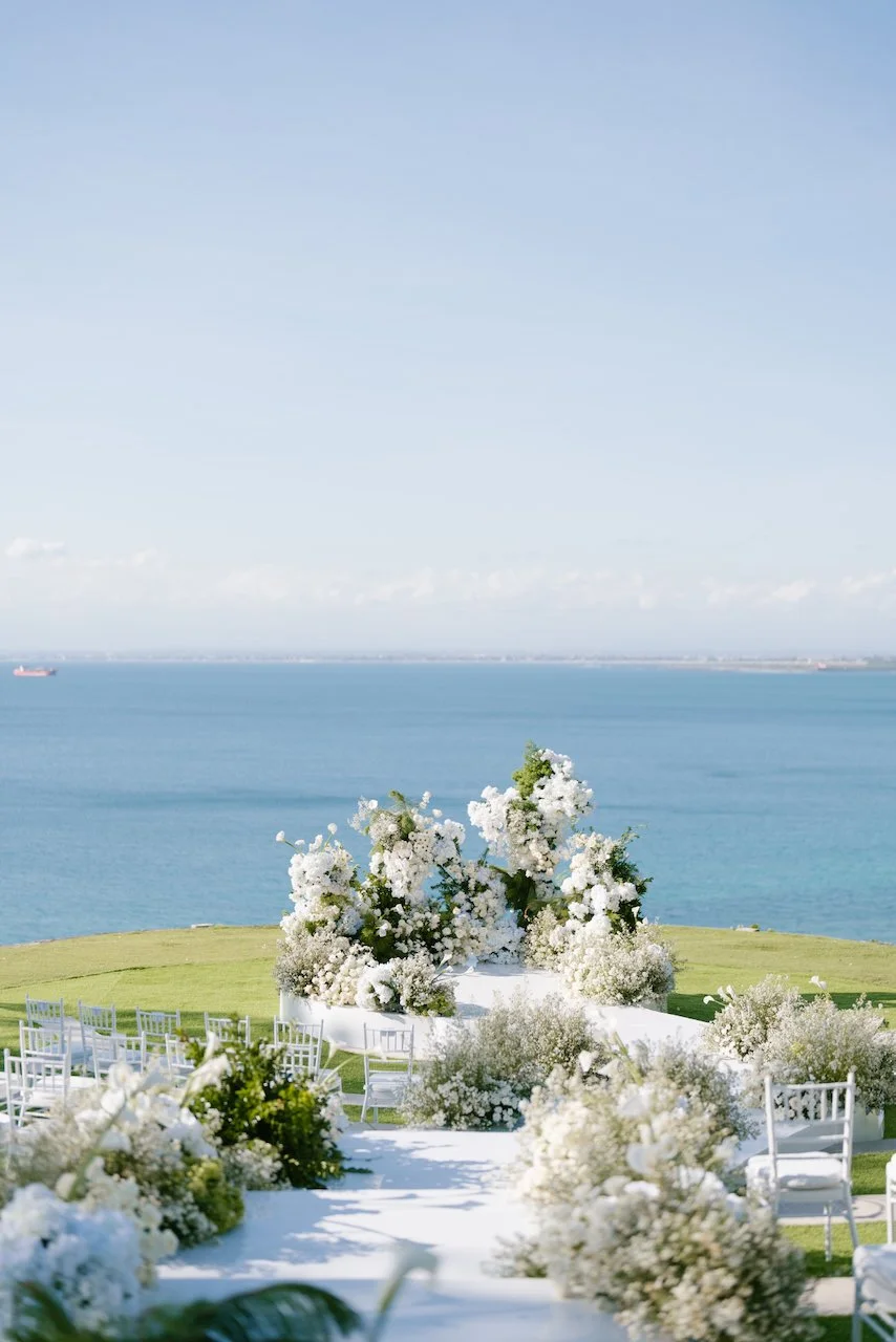 Outdoor wedding ceremony altar with white floral arrangements overlooking the ocean at Ayana Bali