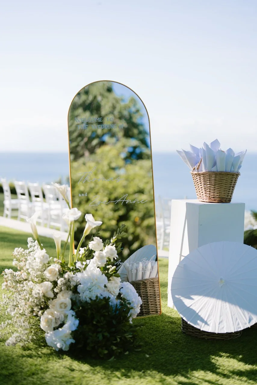 Welcome mirror sign and white floral decor on the oceanfront lawn at Ayana Resort