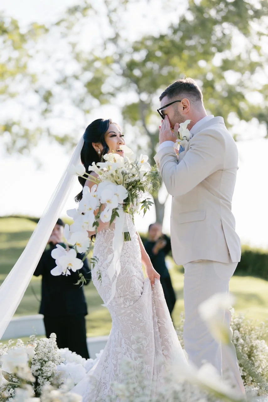 Thomas and Zoe sharing a kiss at the altar surrounded by white floral installations