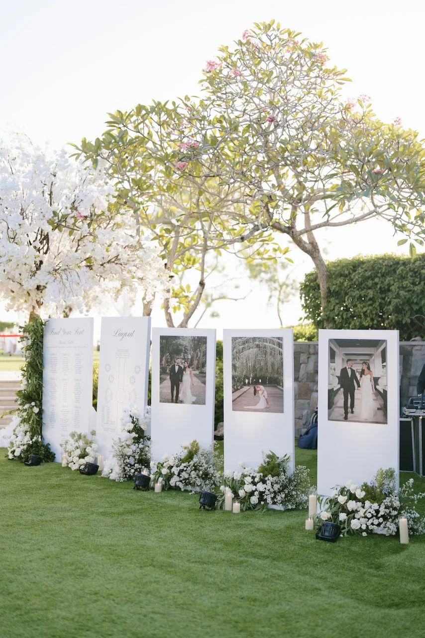 Outdoor gallery wall displaying framed photos on the grass surrounded by white flowers
