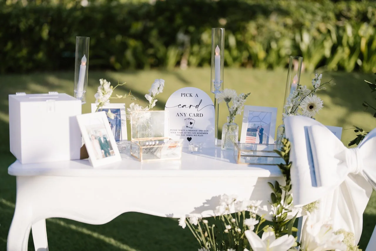 Wedding welcome table featuring custom signage, white florals, and framed photographs