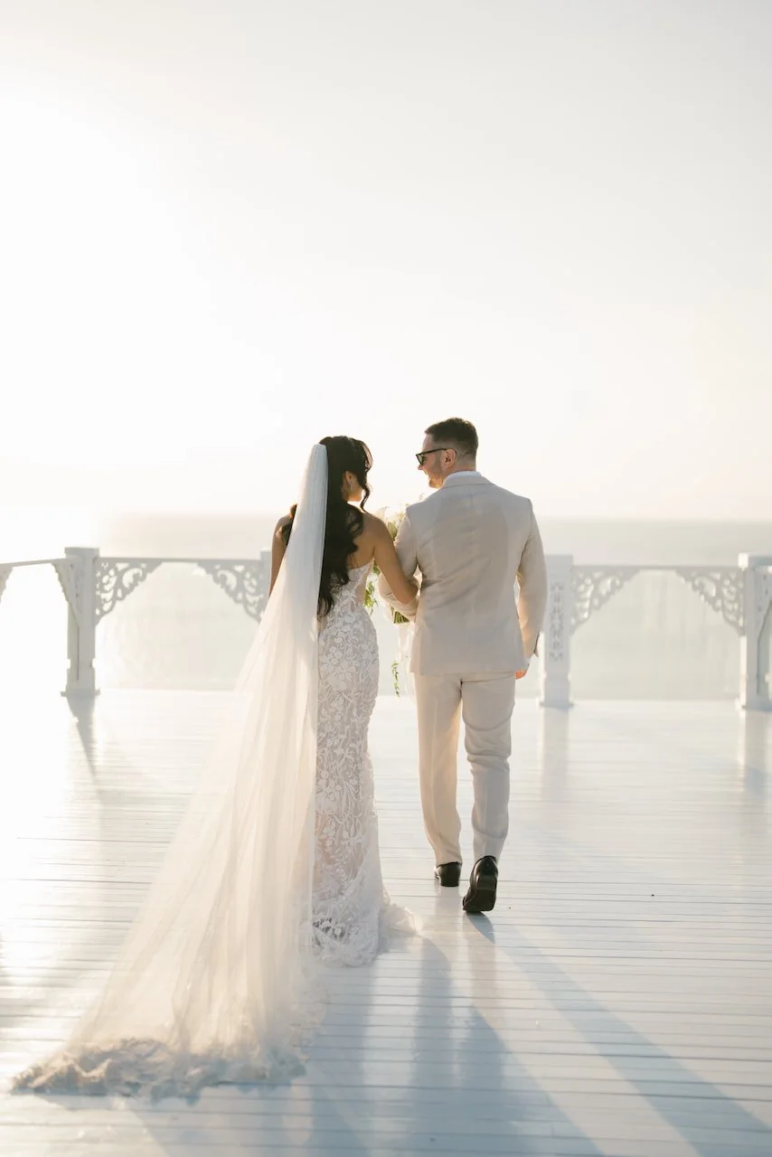 Thomas and Zoe holding hands while walking along a resort pathway at sunset