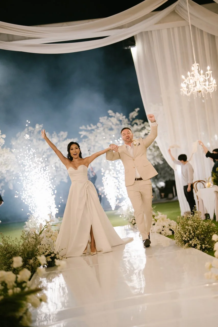 Thomas and Zoe raising their arms in celebration amidst cold sparklers on the dance floor