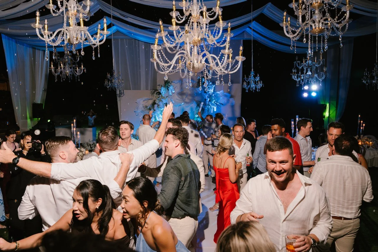 Wedding guests dancing and celebrating under blue party lights on the dance floor