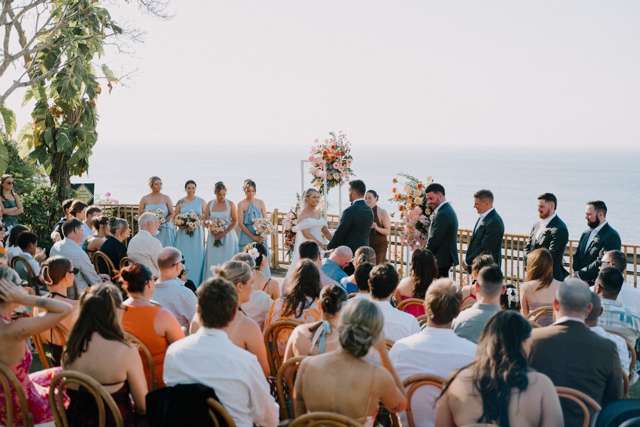 Wide view of the outdoor wedding ceremony with guests seated facing the ocean