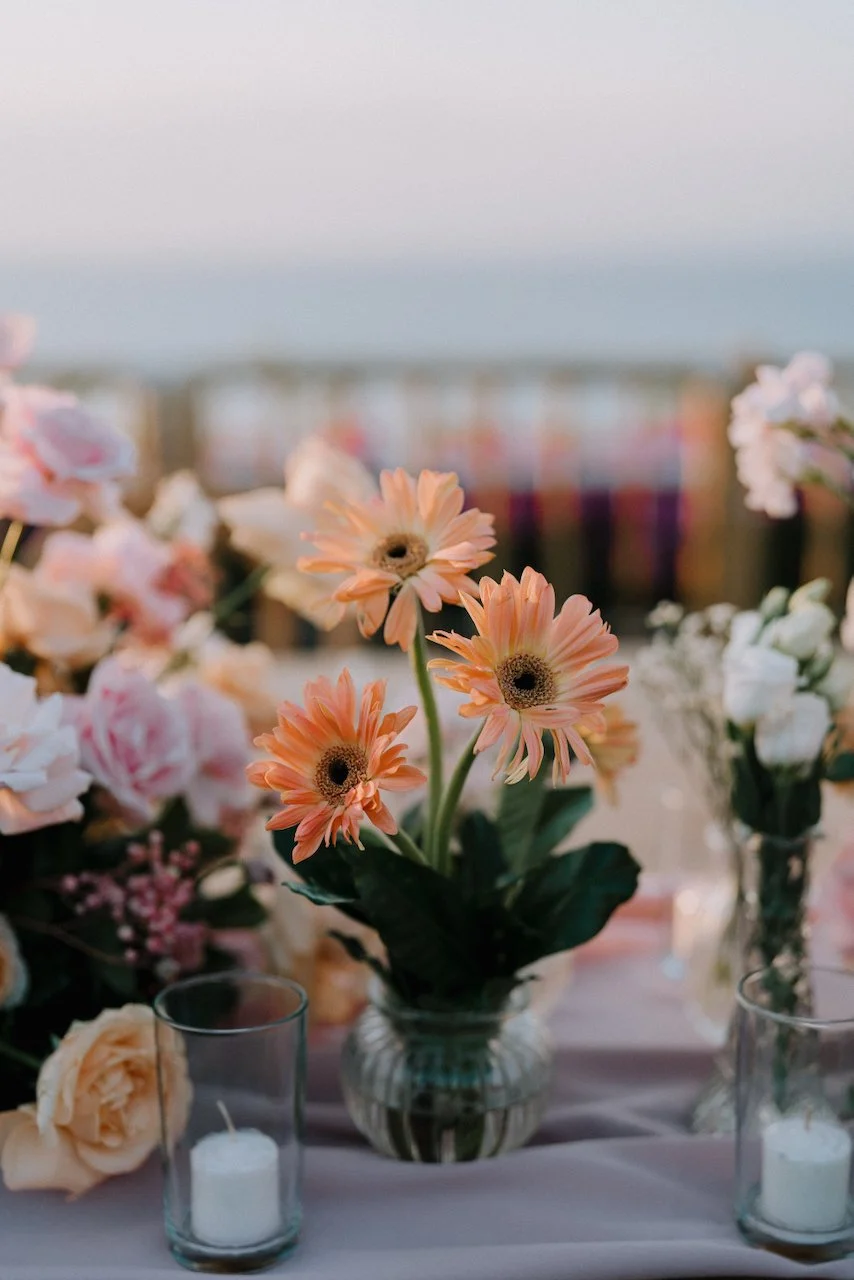 Close up of peach gerbera daisies and pink roses on a wedding reception table