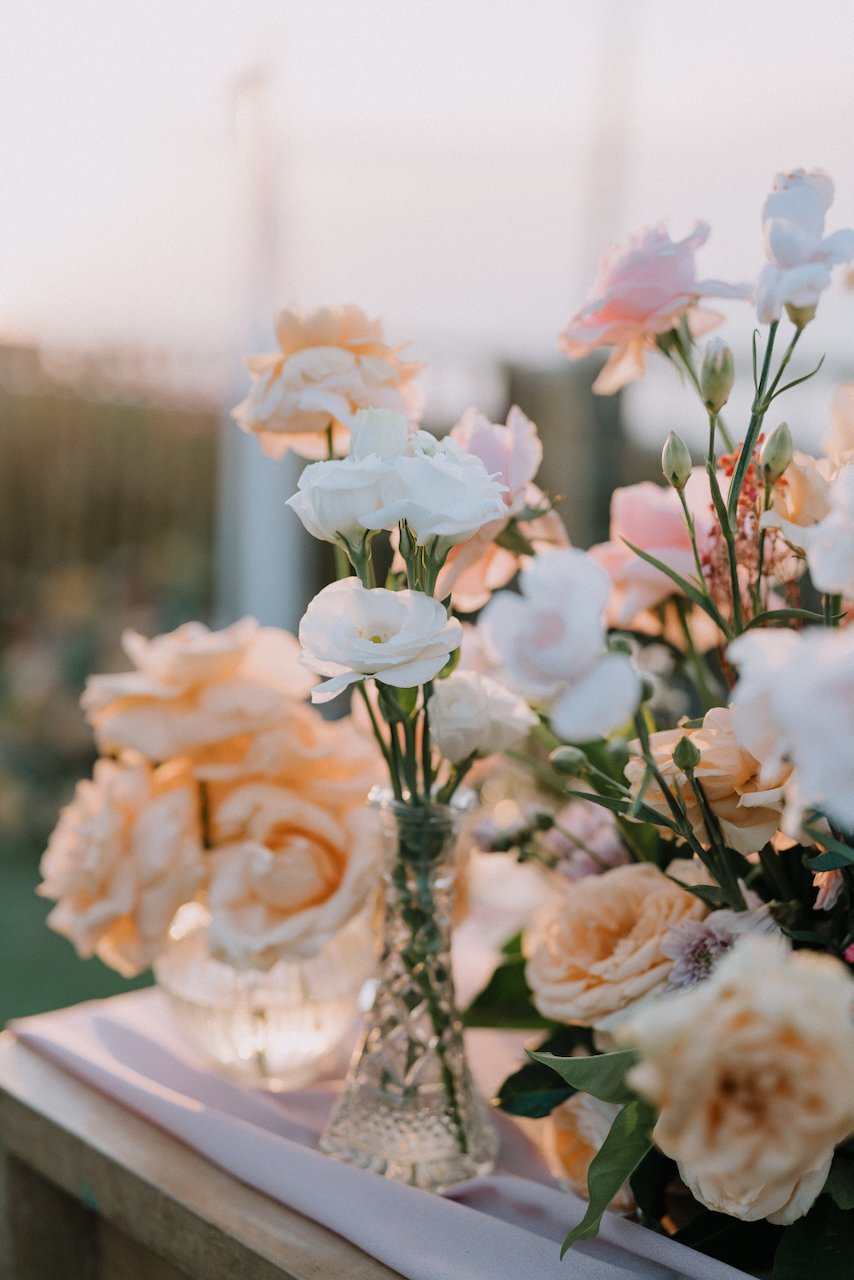 Close up of peach and white floral wedding centerpieces glowing in the sunset light
