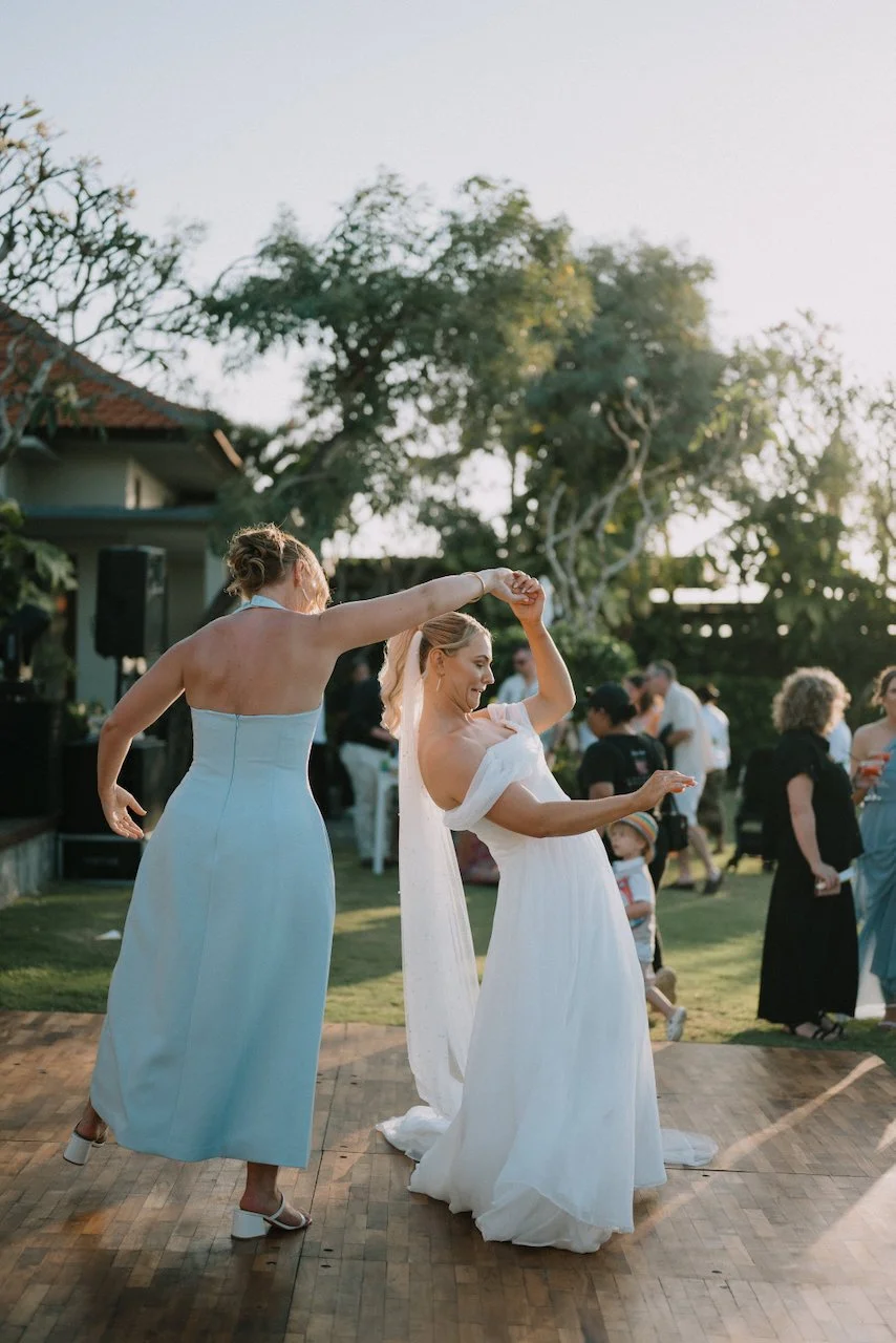 Bride and a bridesmaid dancing together on the outdoor wooden dance floor