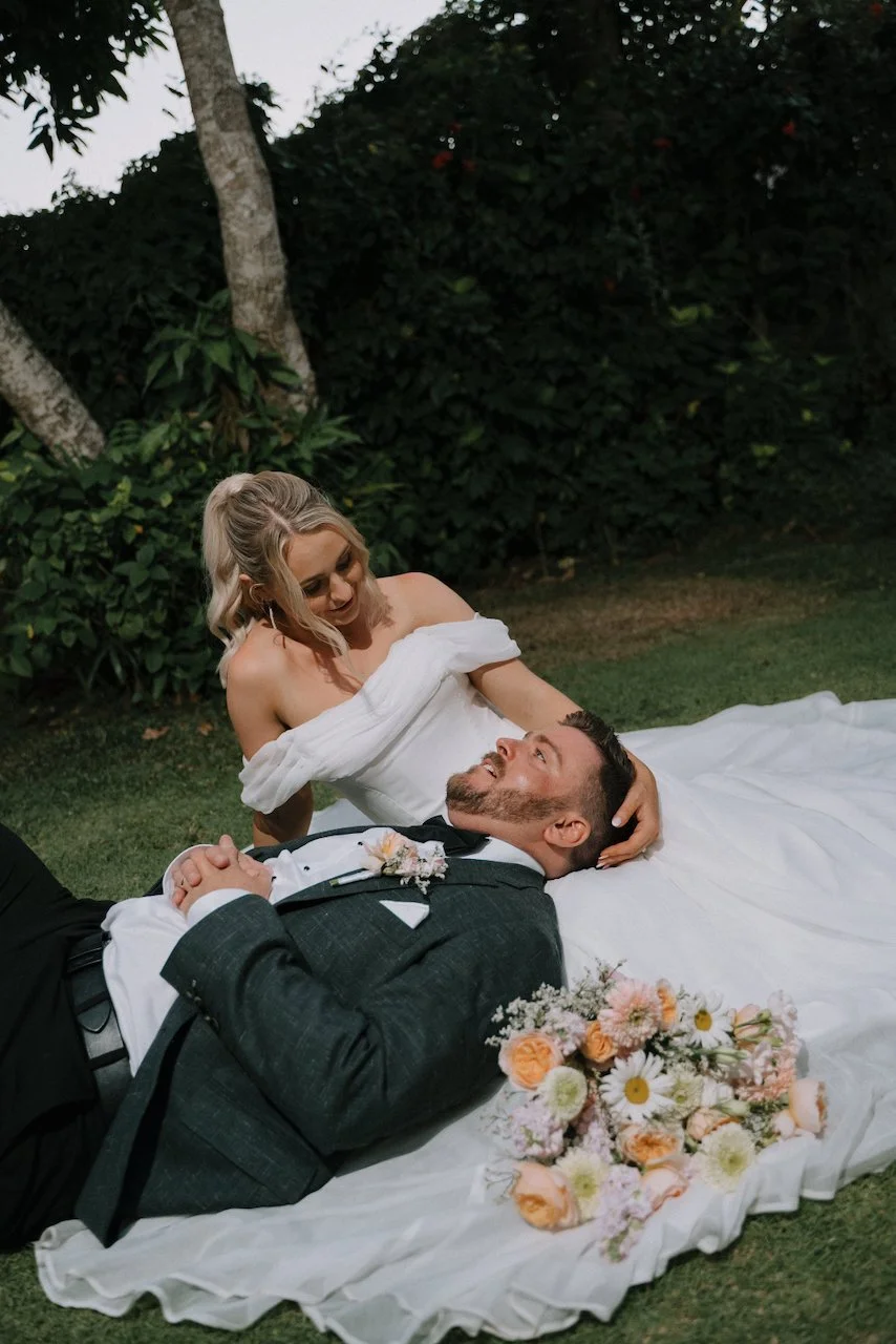 Bride and groom relaxing on the grass with Tegan sitting behind Liam
