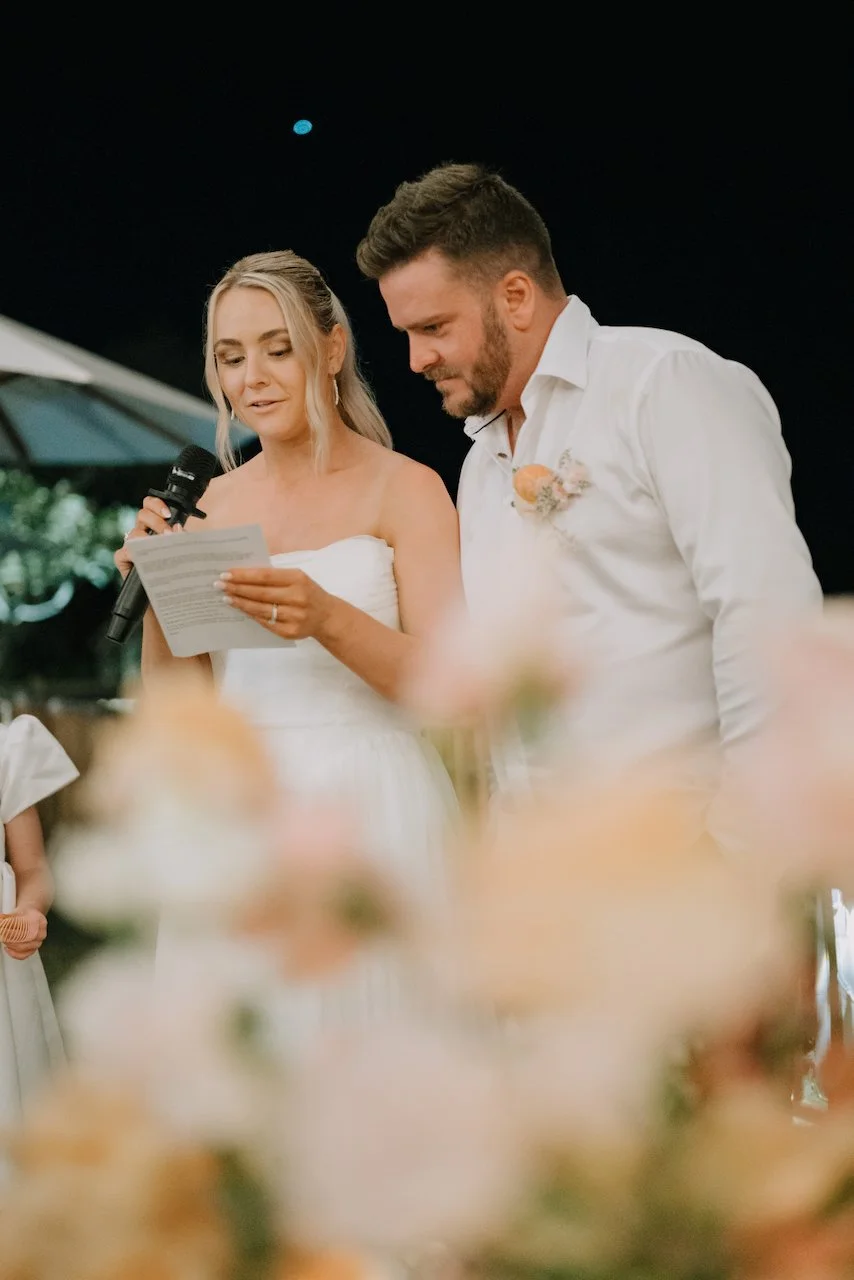 Bride Tegan reading her vows or speech into a microphone next to groom Liam