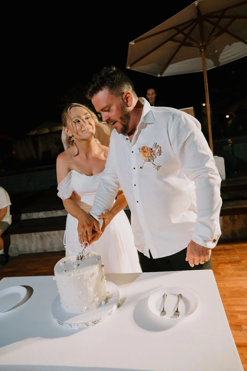Tegan and Liam cutting a white textured wedding cake together outdoors