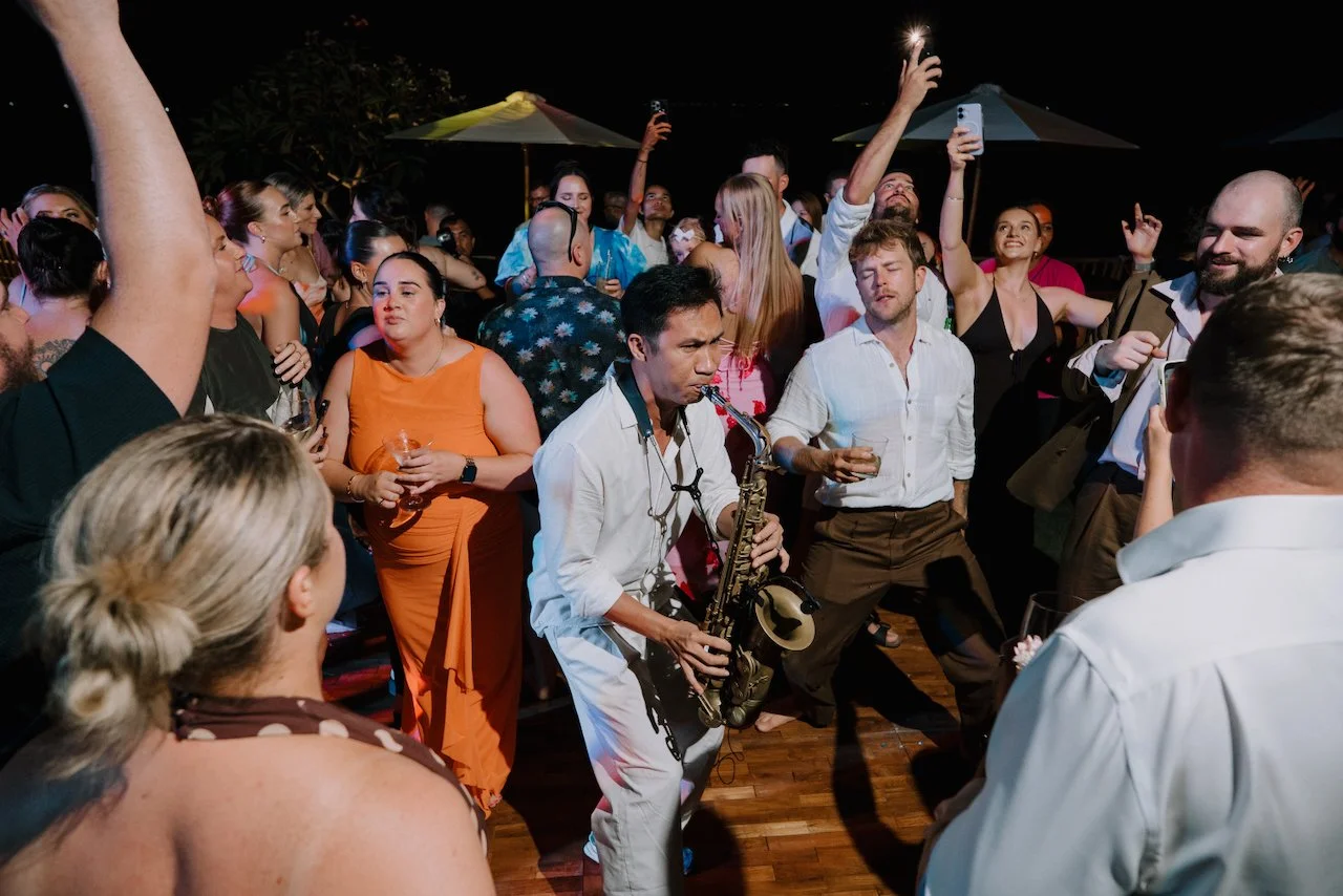 Saxophone player performing on the dance floor surrounded by cheering wedding guests