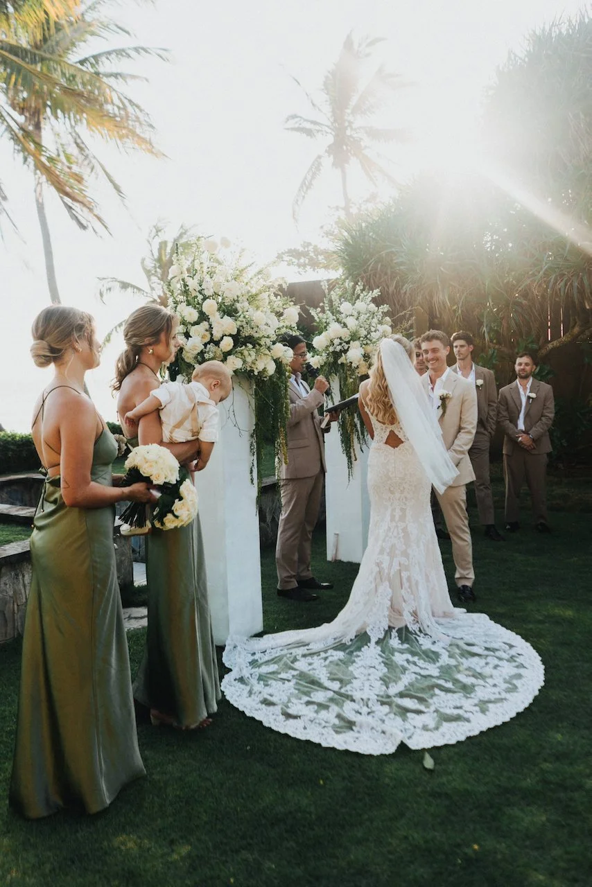 Bridesmaids in olive green dresses standing at the altar during an outdoor Tabanan ceremony