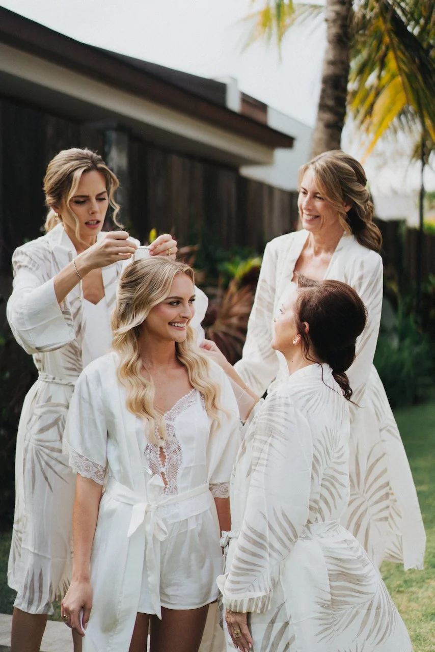 Bride Daniella and her bridesmaids smiling in matching white robes before the wedding