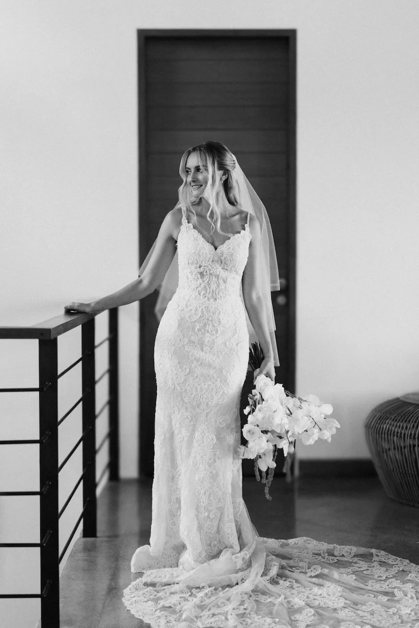 Black and white portrait of the bride holding white orchids in her lace wedding gown