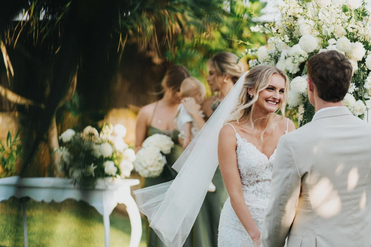 Groom Devin smiling at Daniella during their tropical garden wedding ceremony